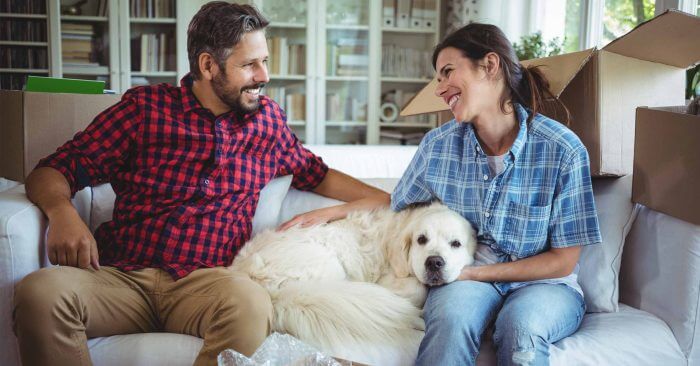 homeowners sitting on the couch with their dog while they're taking a break from unpacking
