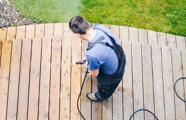 homeowner cleaning deck outside of their home to prepare for summer