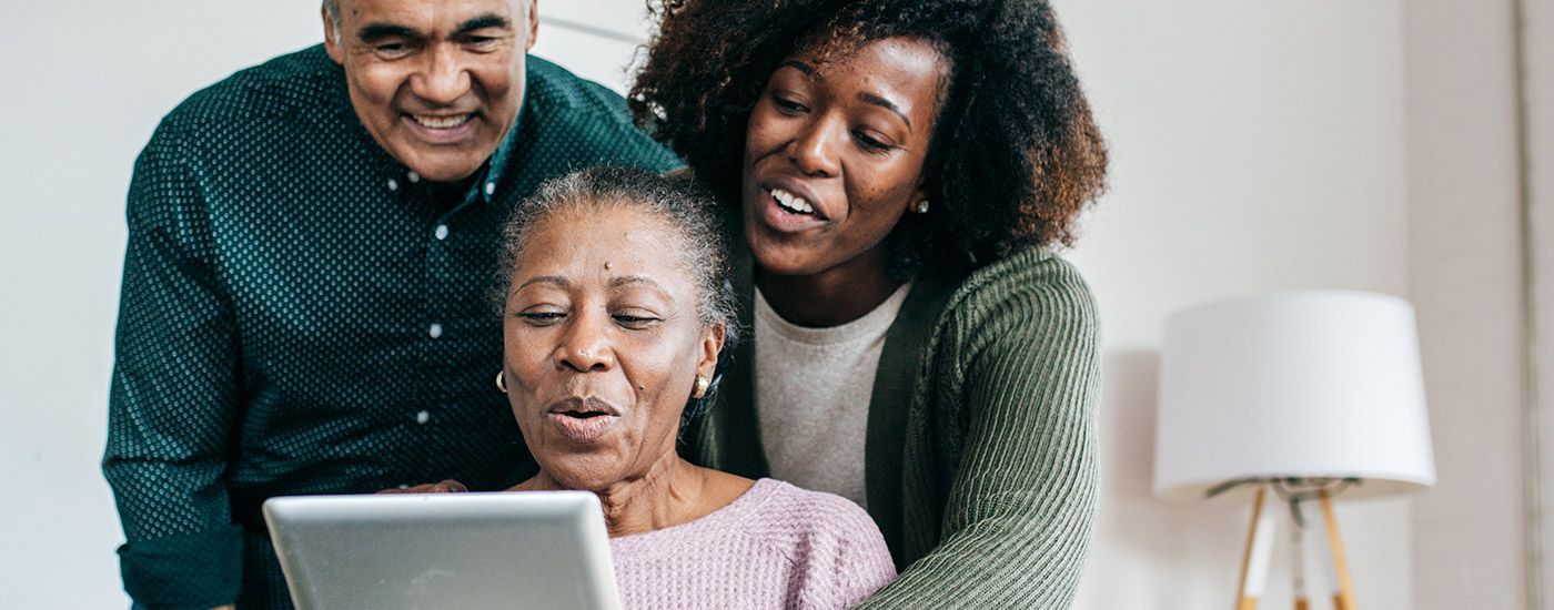 A young woman showing an older couple a tablet.