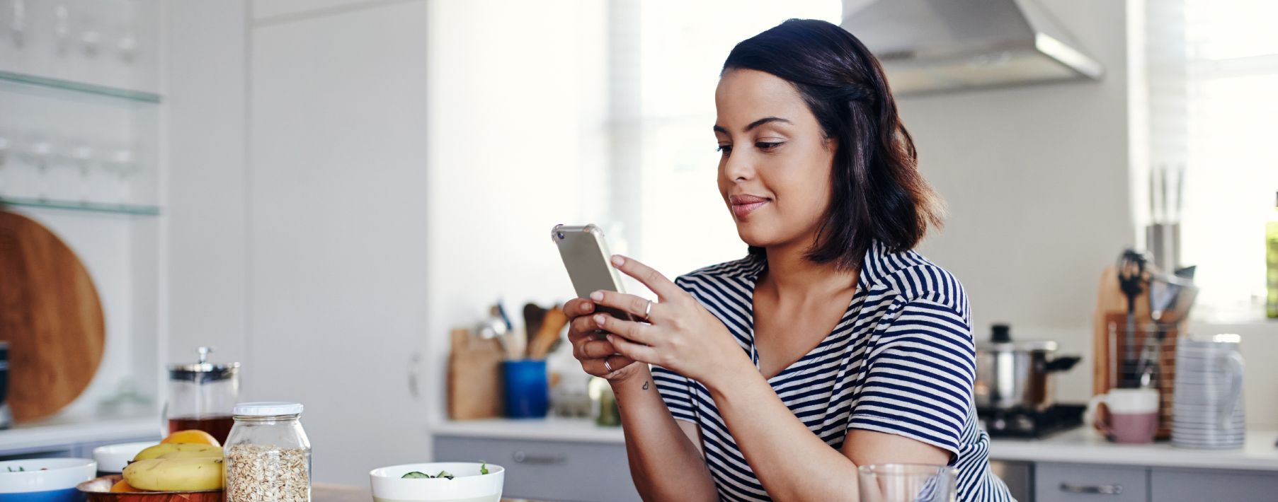 A woman looking at her cell phone in the kitchen