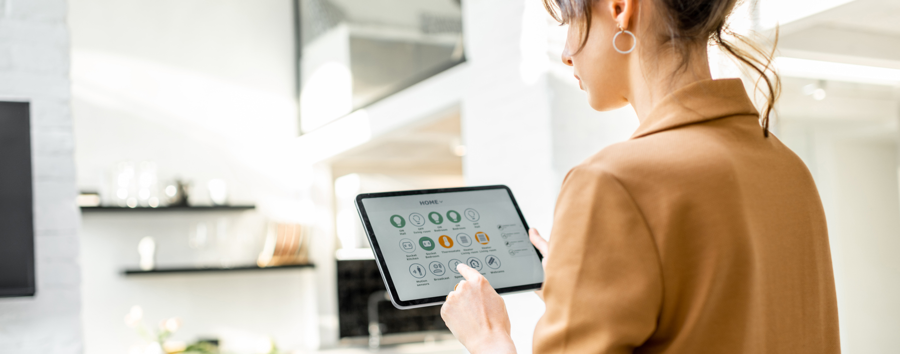 Woman in an orange shirt touches the screen of an iPad that is showing a smart thermostat application.