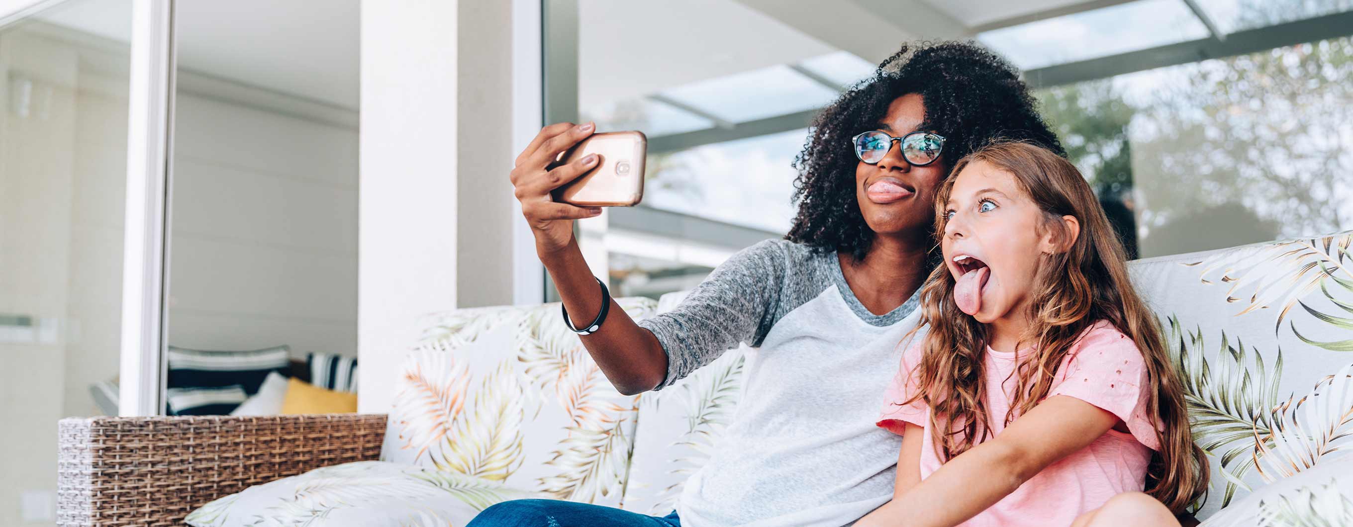 Woman and child sit on the couch taking a selfie. 