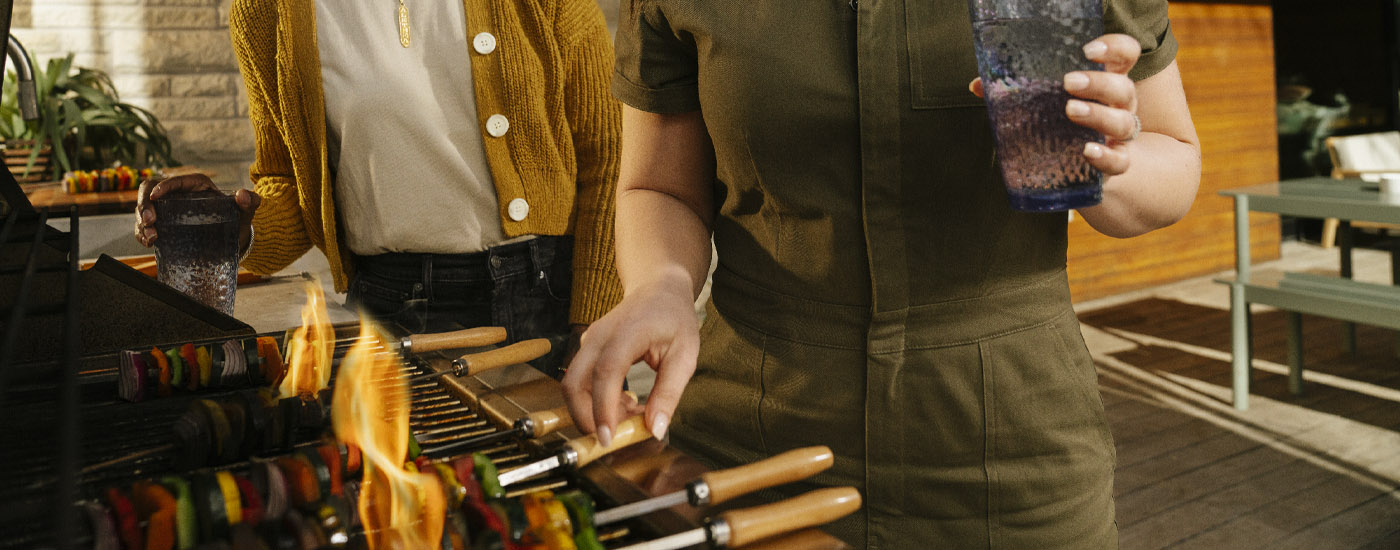 couple grilling skewers outside of their home