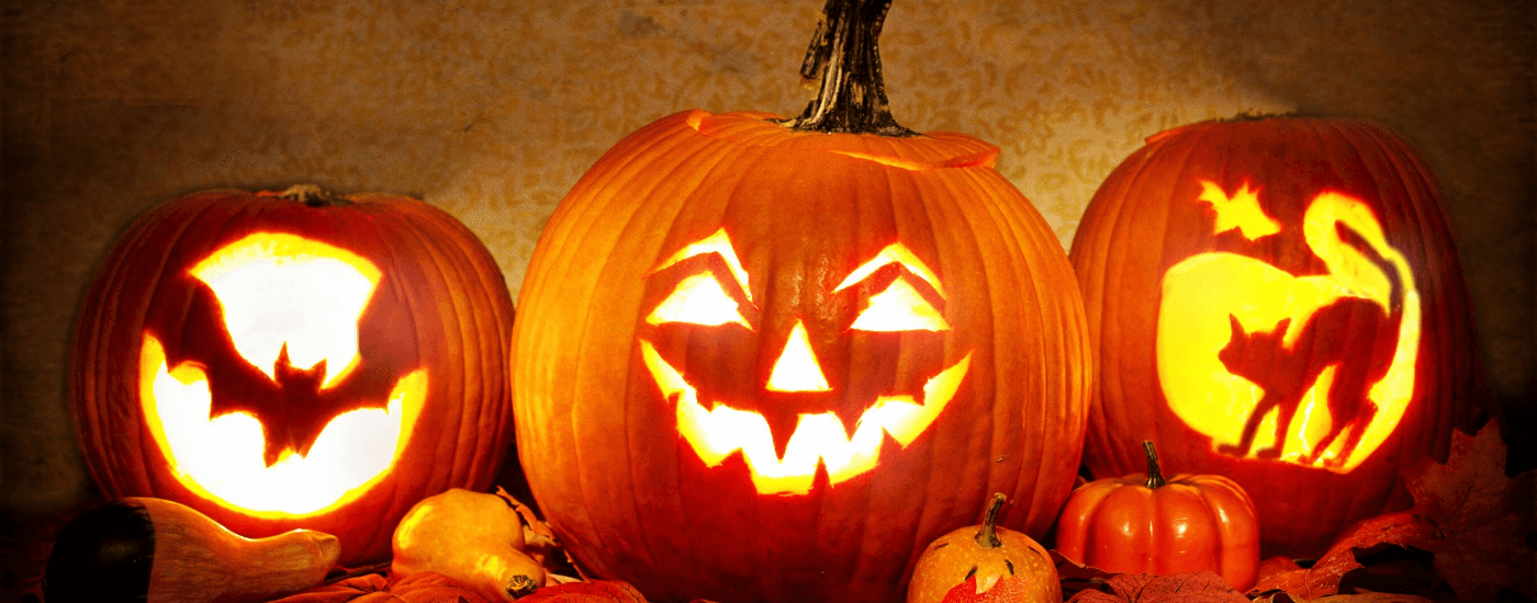 three pumpkins with varying designs with lights inside