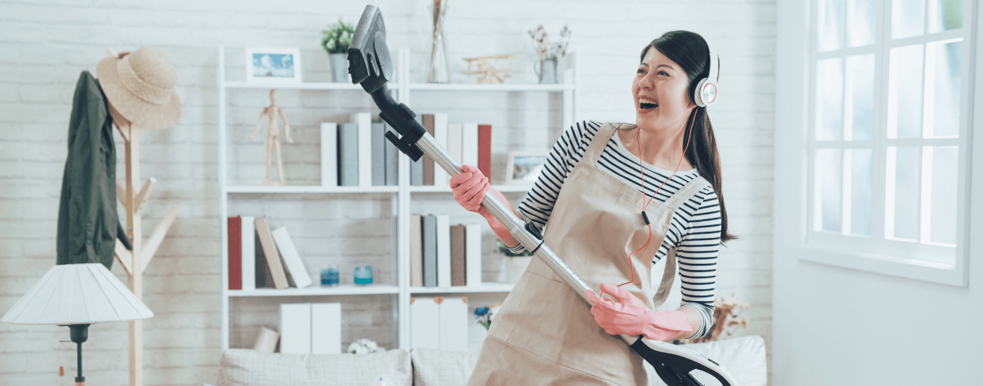 happy homeowner listening to music and holding up a vacuum