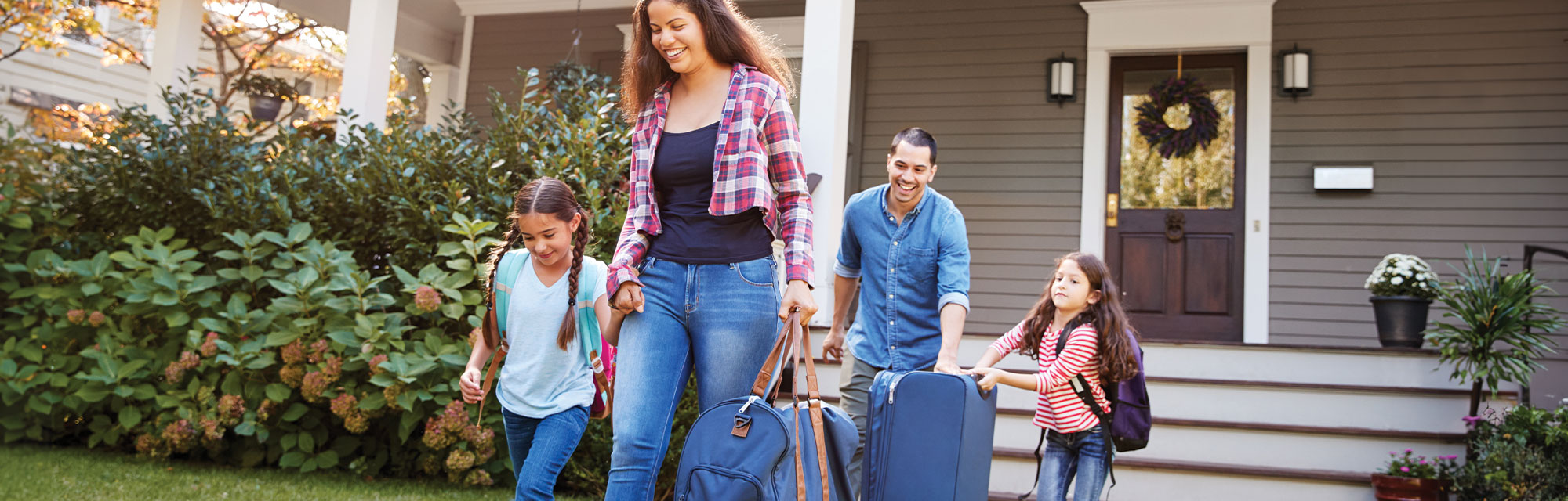 family of four walking away from their home to go on vacation