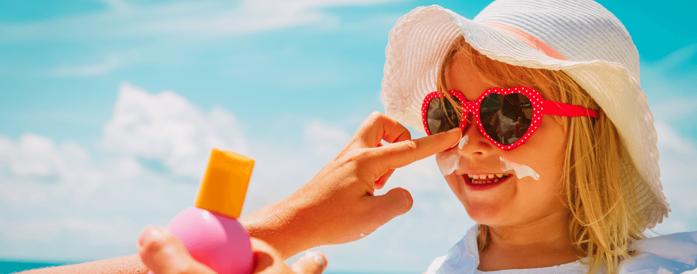 child getting sunscreen applied on their face by an adult