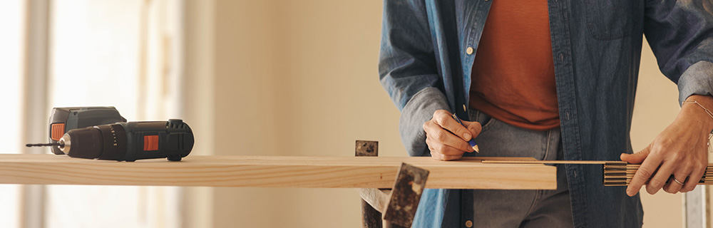 homeowner measuring a piece of wood to prepare for a DIY project
