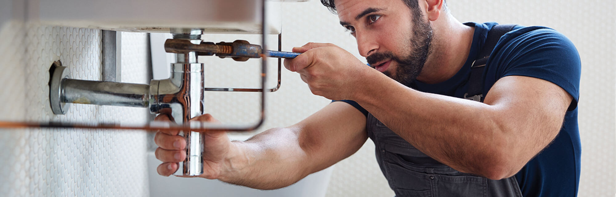 homeowner tightening pipes under bathroom sink