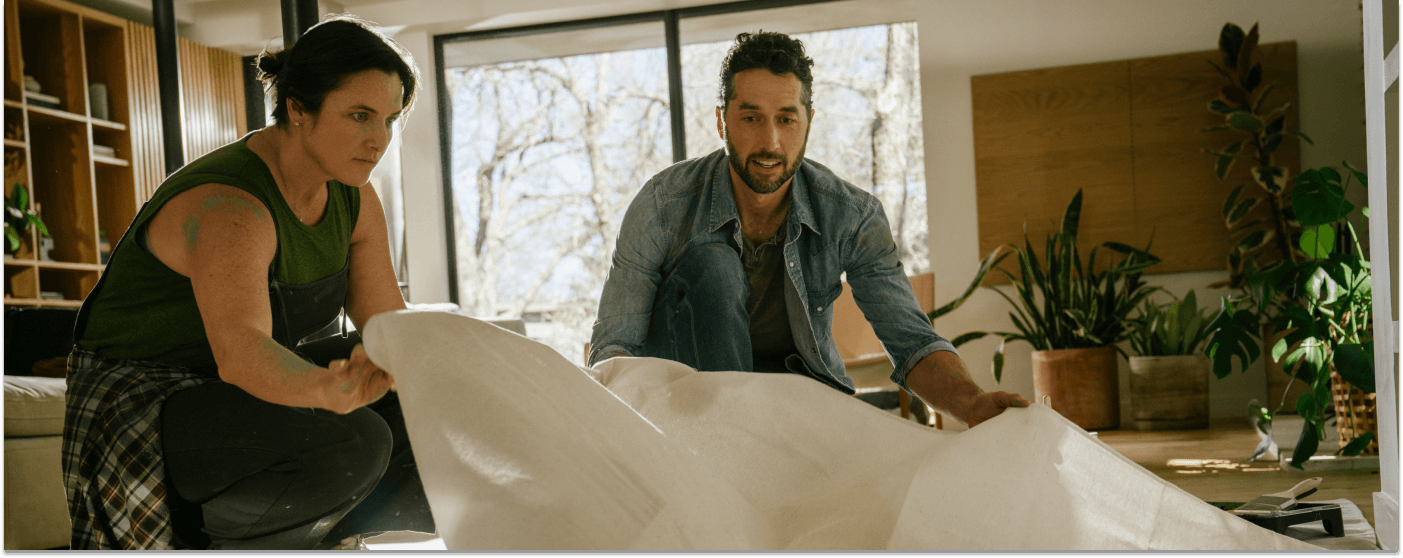 couple putting down a tarp on the floor to get ready for a home renovation