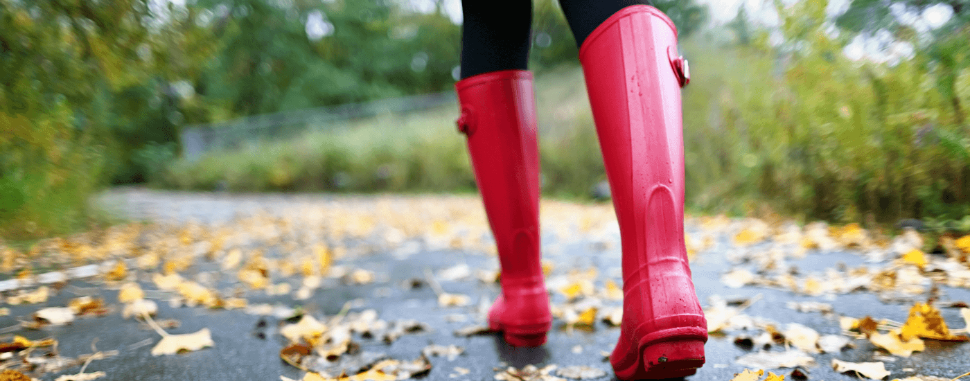 homeowner wearing red boots walking down their street that's covered with leaves
