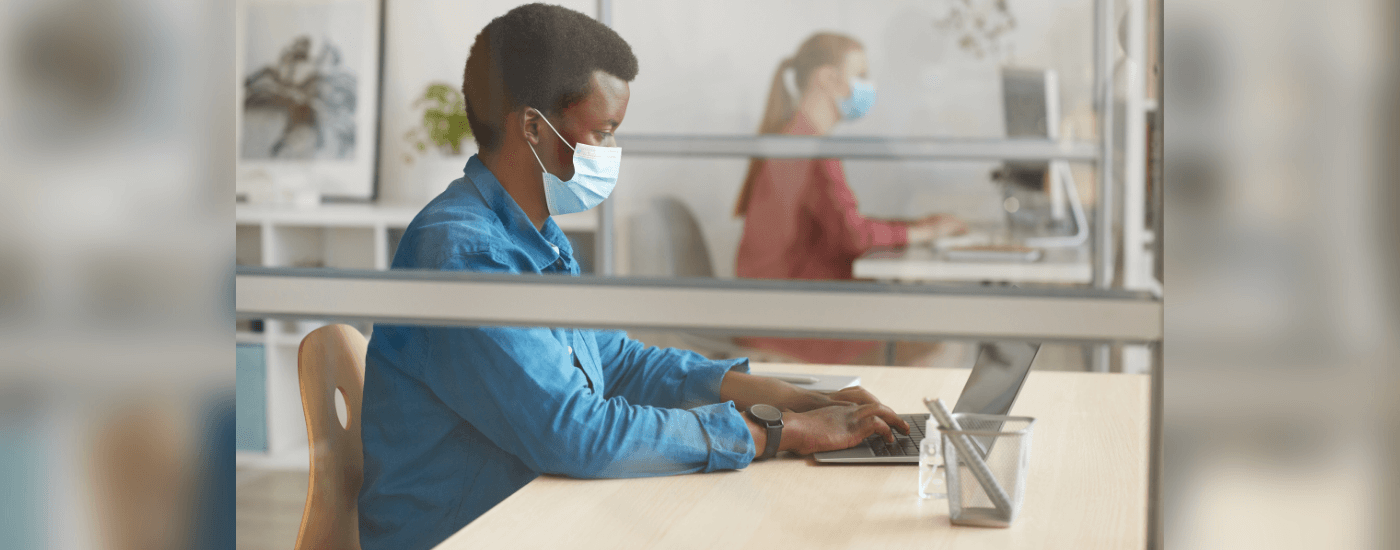 remote worker wearing a mask while they work on their laptop in the office
