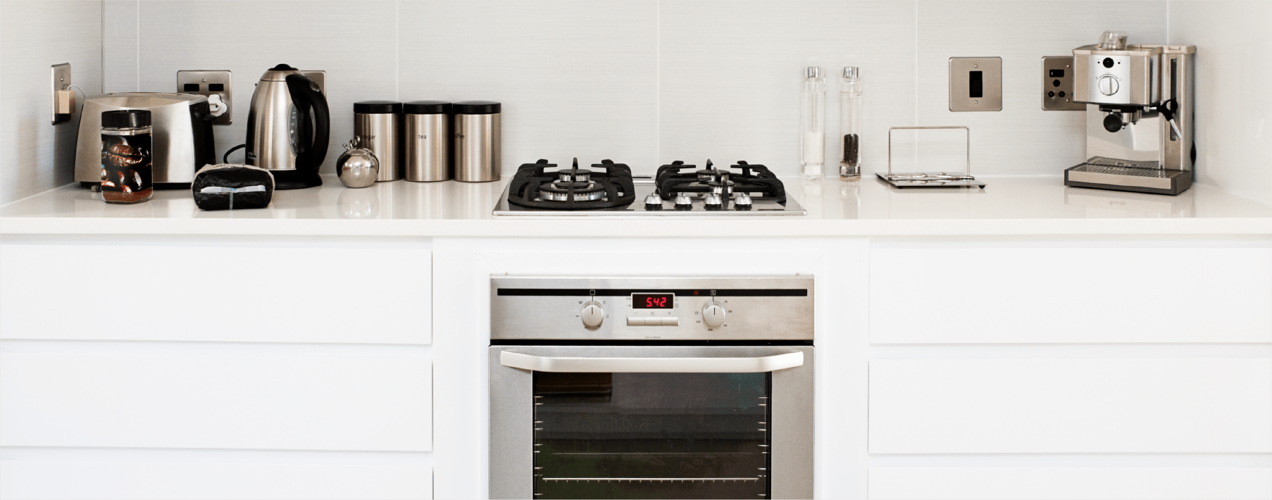 Image of a stove and various stainless steel appliances in a white kitchen