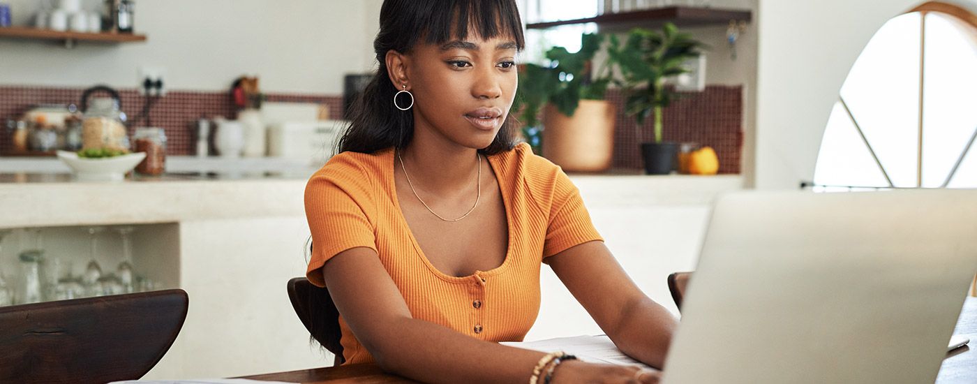 A woman sitting at the kitchen table looking at a laptop