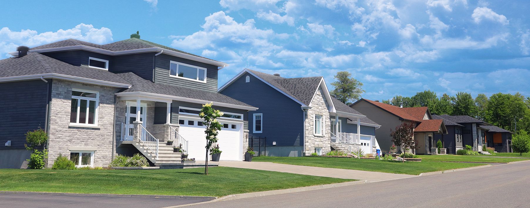 Image of a street with several houses next to each other and a blue sky behind them