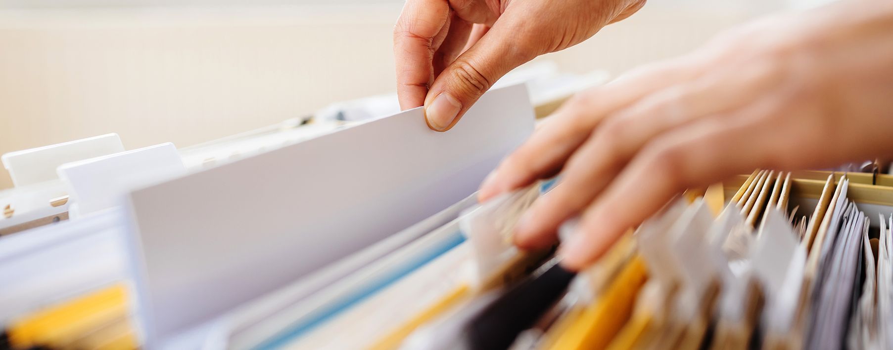 Image of two hands going through files in a drawer