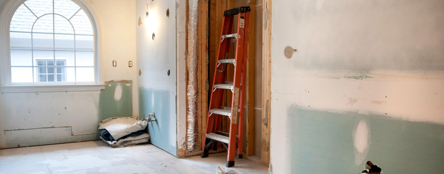 Image of a ladder in an unfinished room with a window
