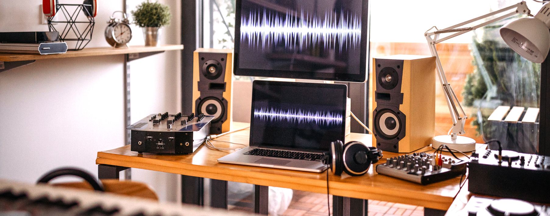 A desk with a laptop, a monitor, speakers and other music equipment