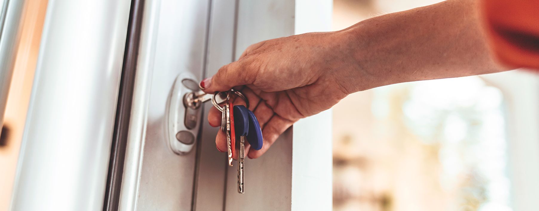 A woman's hand using keys to unlock her front door