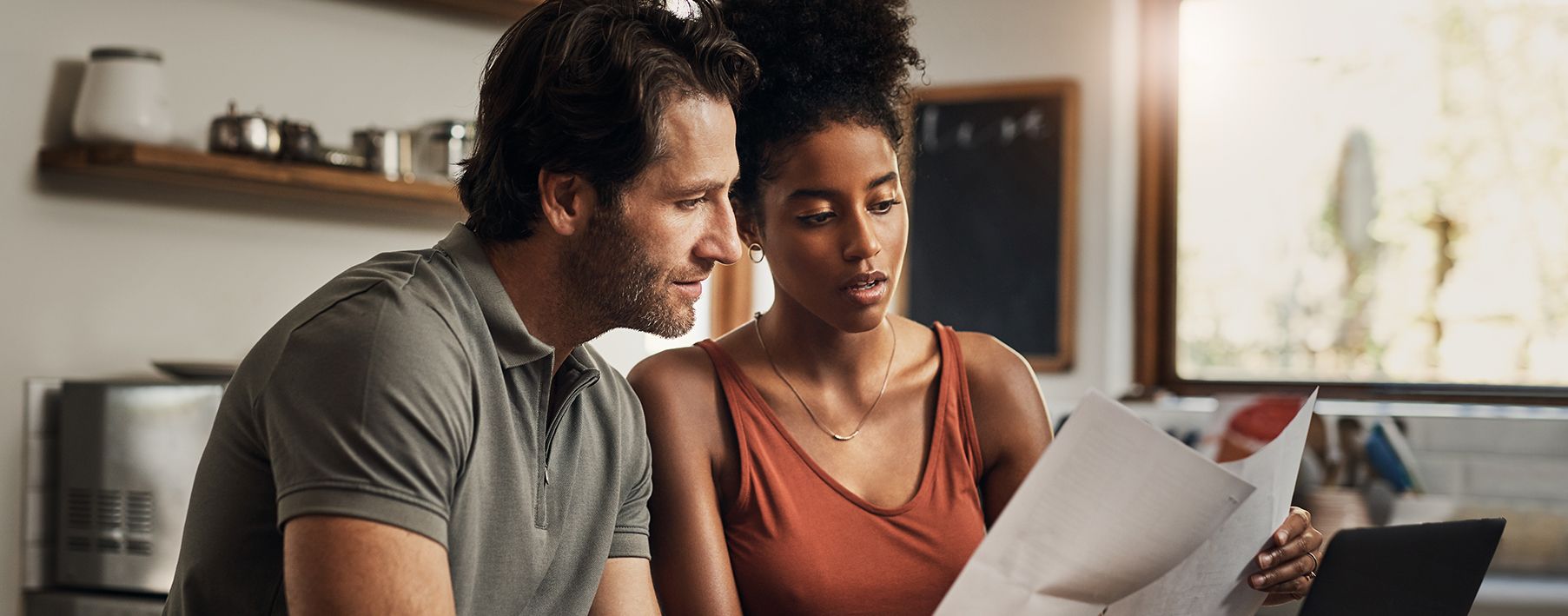 A man and a woman looking a papers in a kitchen