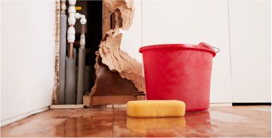 Image of a damaged wall with water a sponge and a bucket on the ground