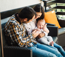 couple holding a baby sitting on the porch