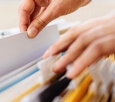 person searching papers in a file cabinet