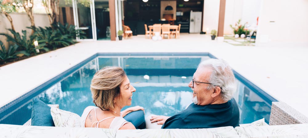 Two people talk in front of a pool.