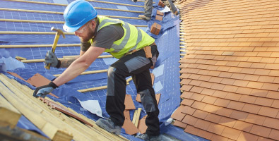 man working on roof with blue construction helmet