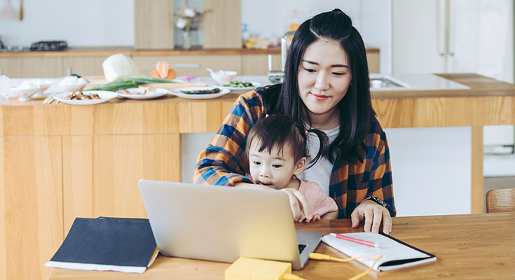 A mom and child using a laptop at the kitchen table