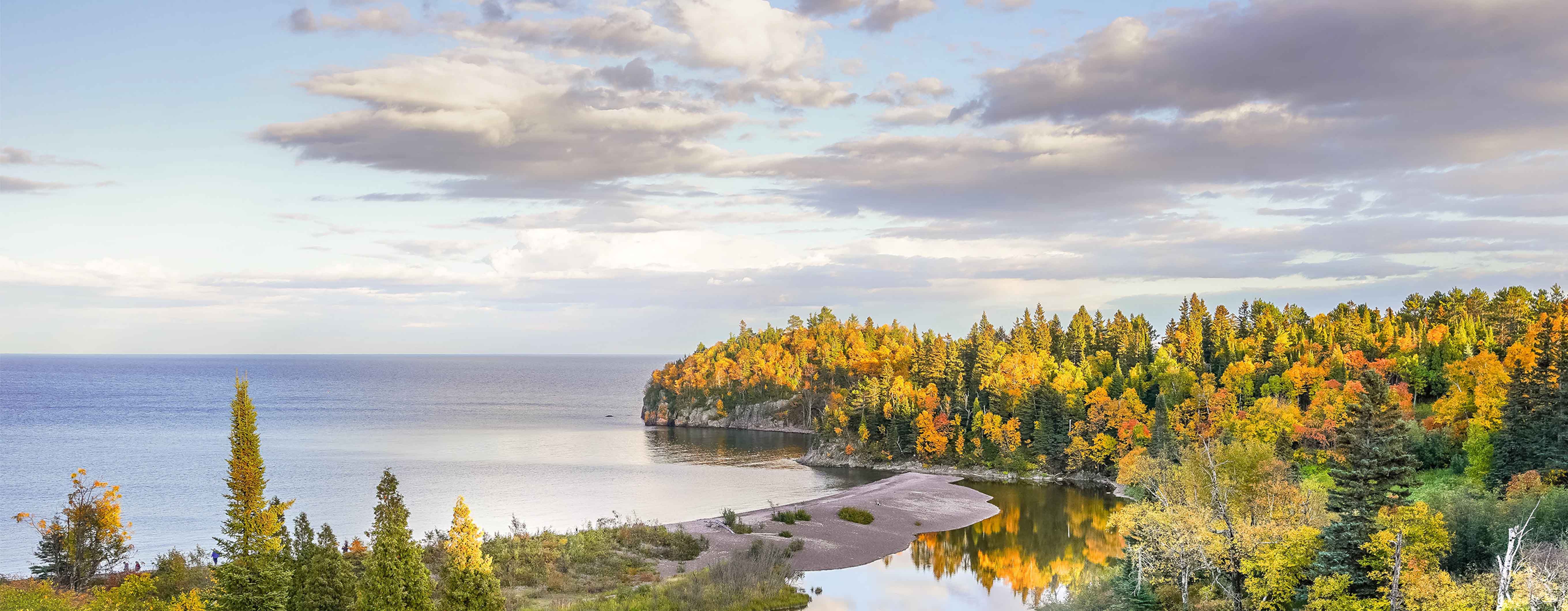 Image of a body of water surrounded by trees in the fall