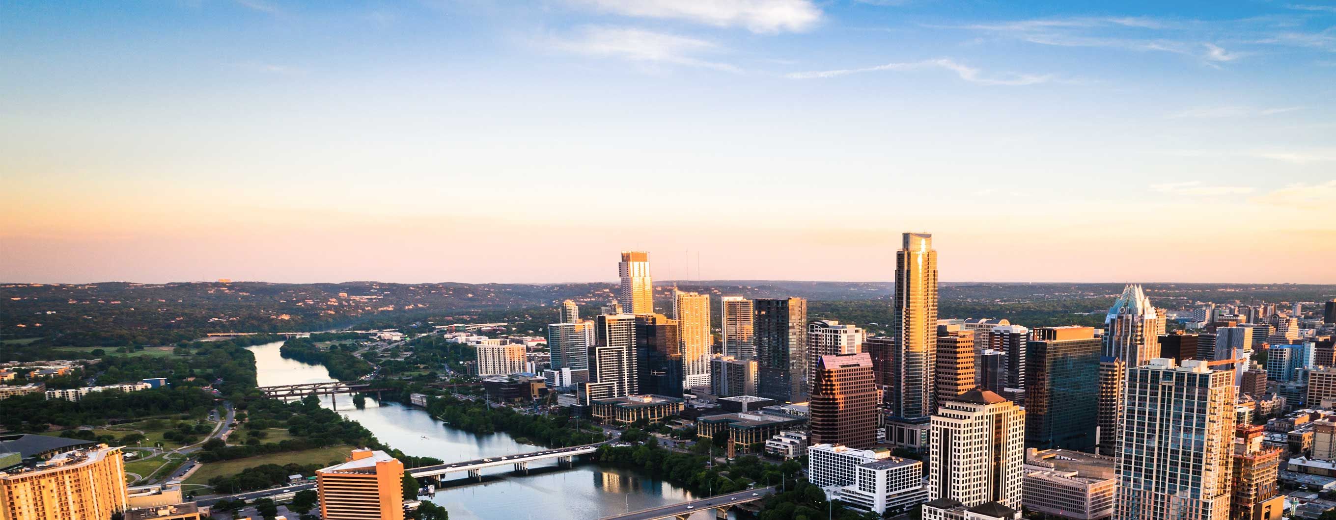 Image of the Austin city skyline and lake with a blue sky with scattered clouds