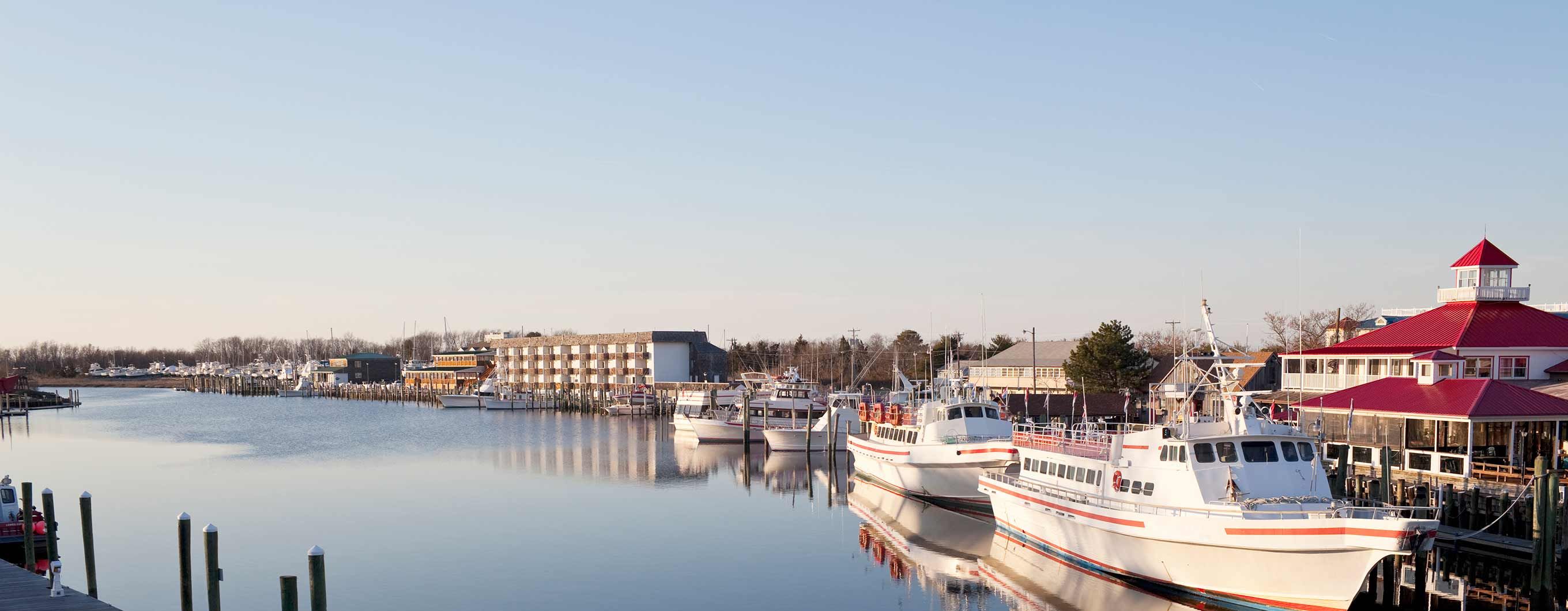 Image of a a body of water with boats tied up to decks next to multiple buildings