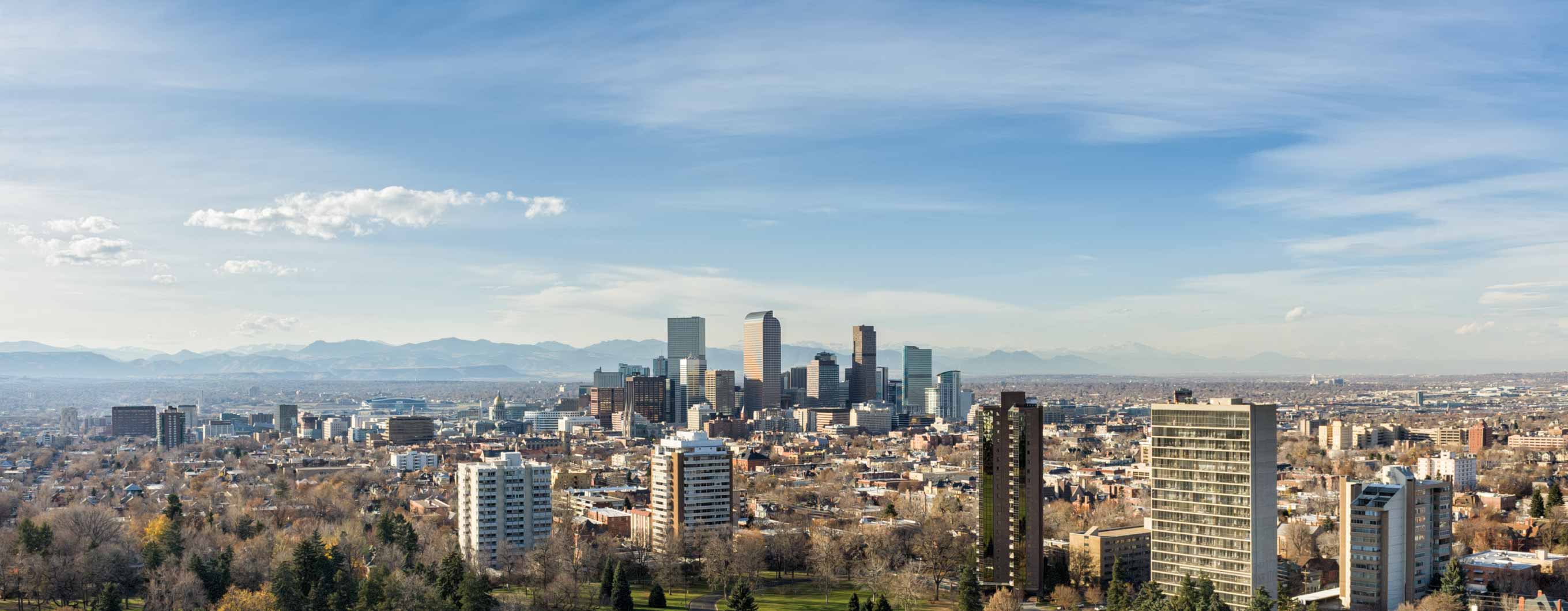 Image of the Denver city skyline with clouds and mountains in the background