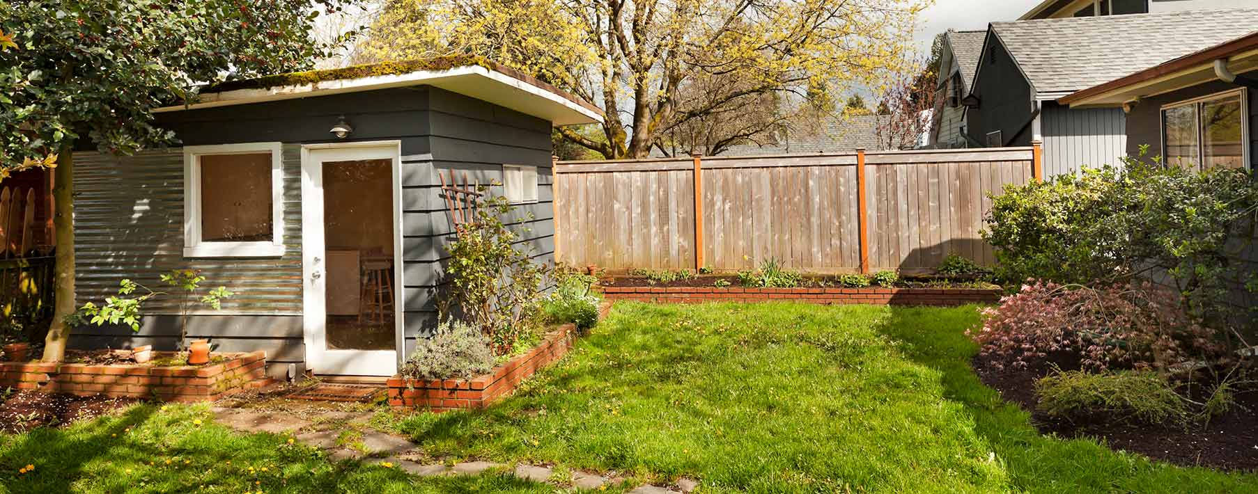A garden shed sits in a lush, green yard.