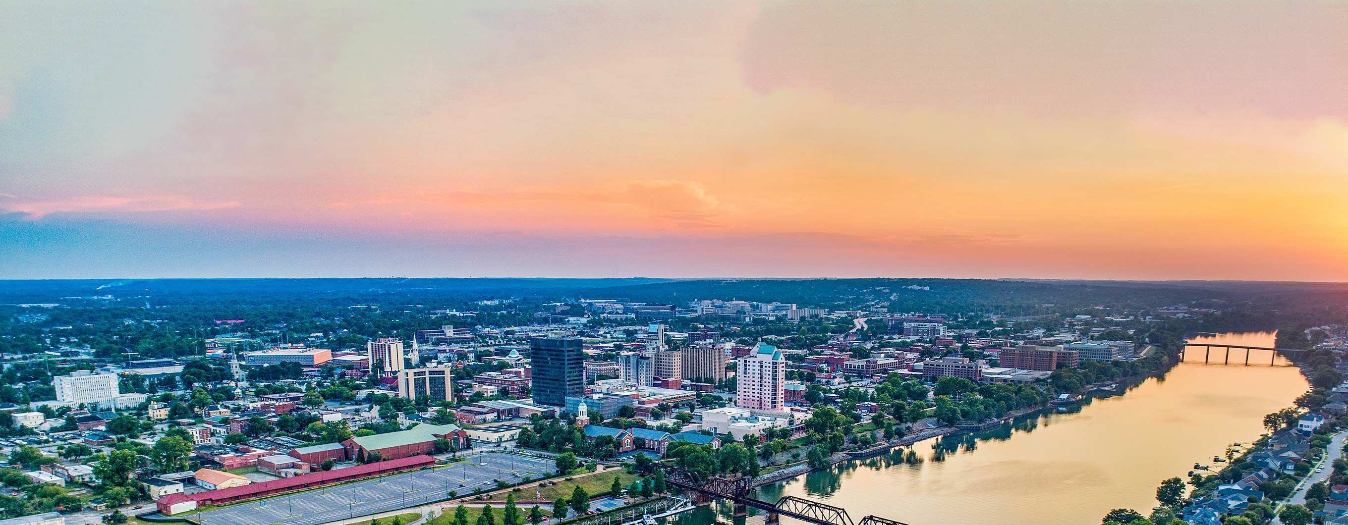 Image of a city by the water with the sun setting behind it