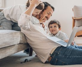 Man sitting on the floor with a laptop, his sons around him