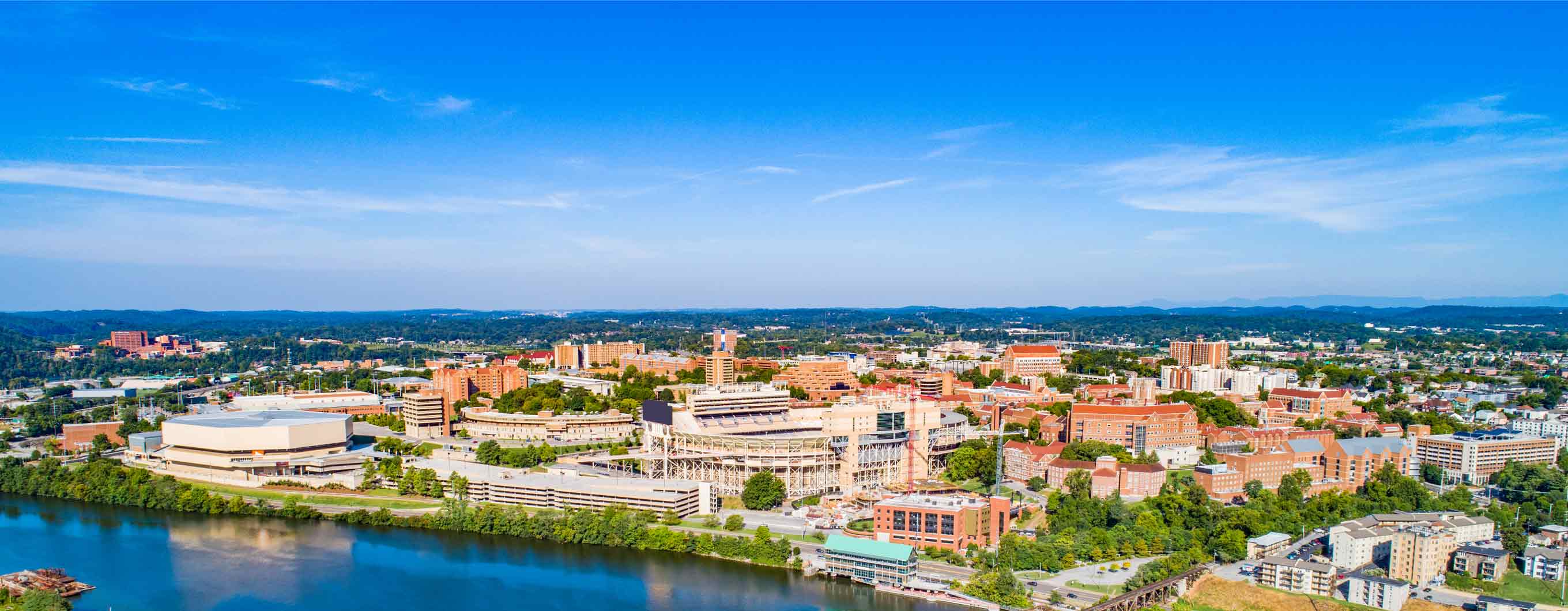 The top half is a blue sky speckled with clouds, and the bottom half is the Knoxville skyline.