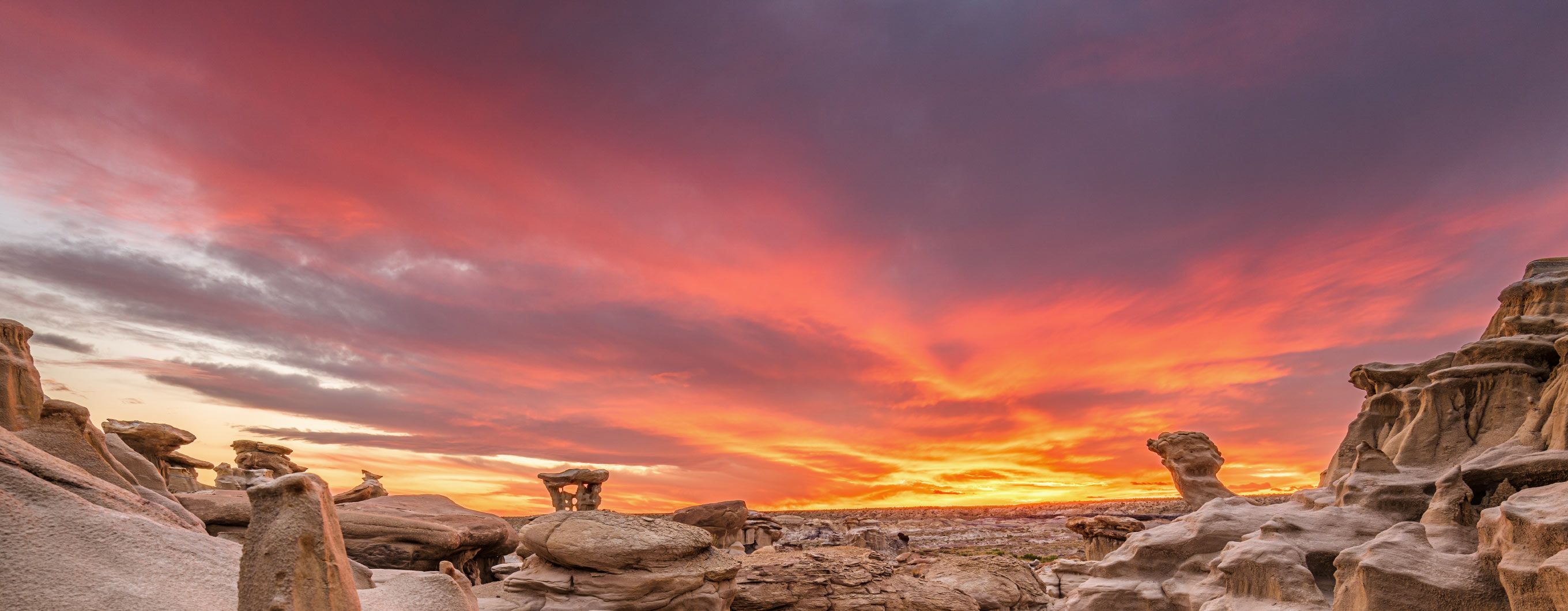 Image of a rocky landscape in New Mexico with a cloudy sky and a setting sun