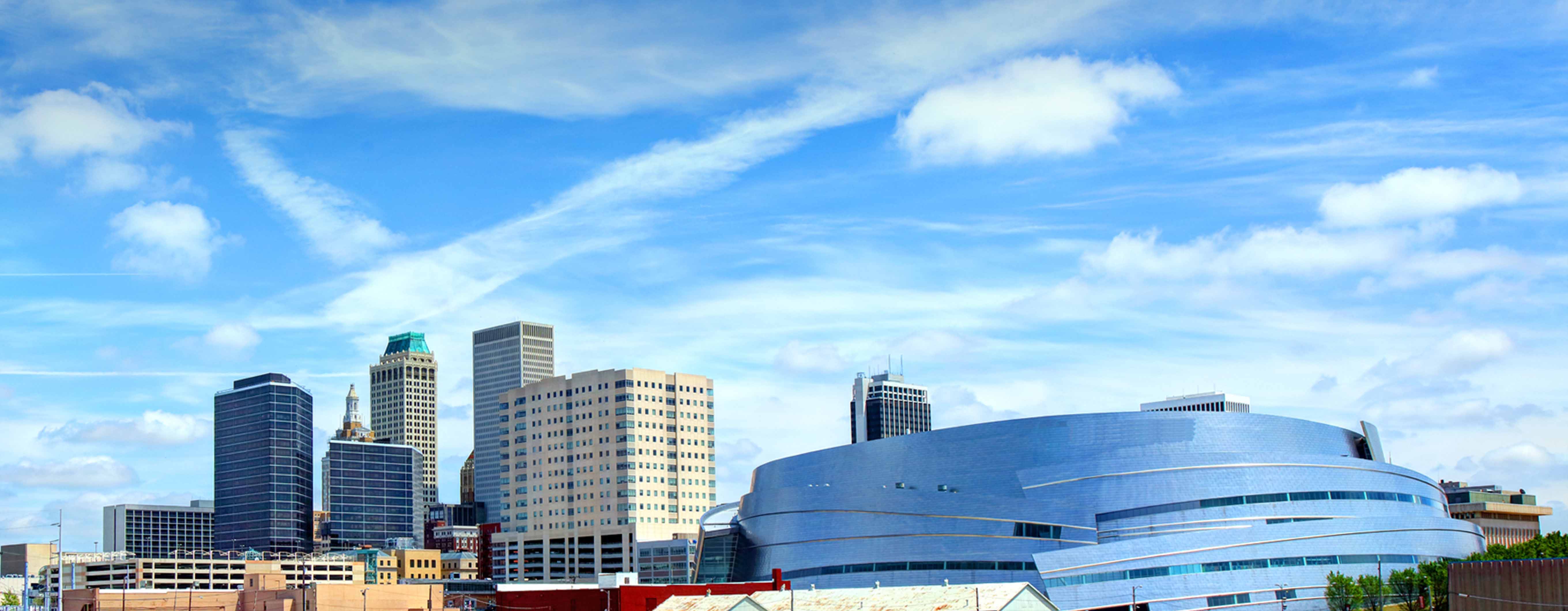 Skyline of Oklahoma City on a sunny day, with several white clouds in the sky.