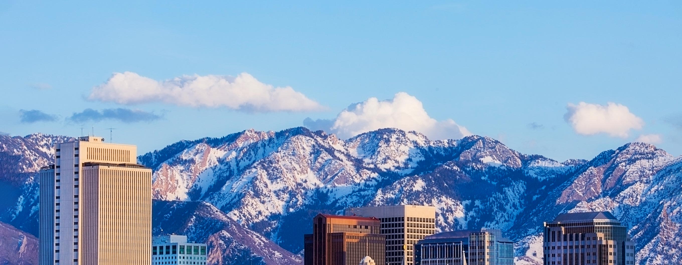 Image of the tops of buildings in Salt Lake City with the mountains behind them