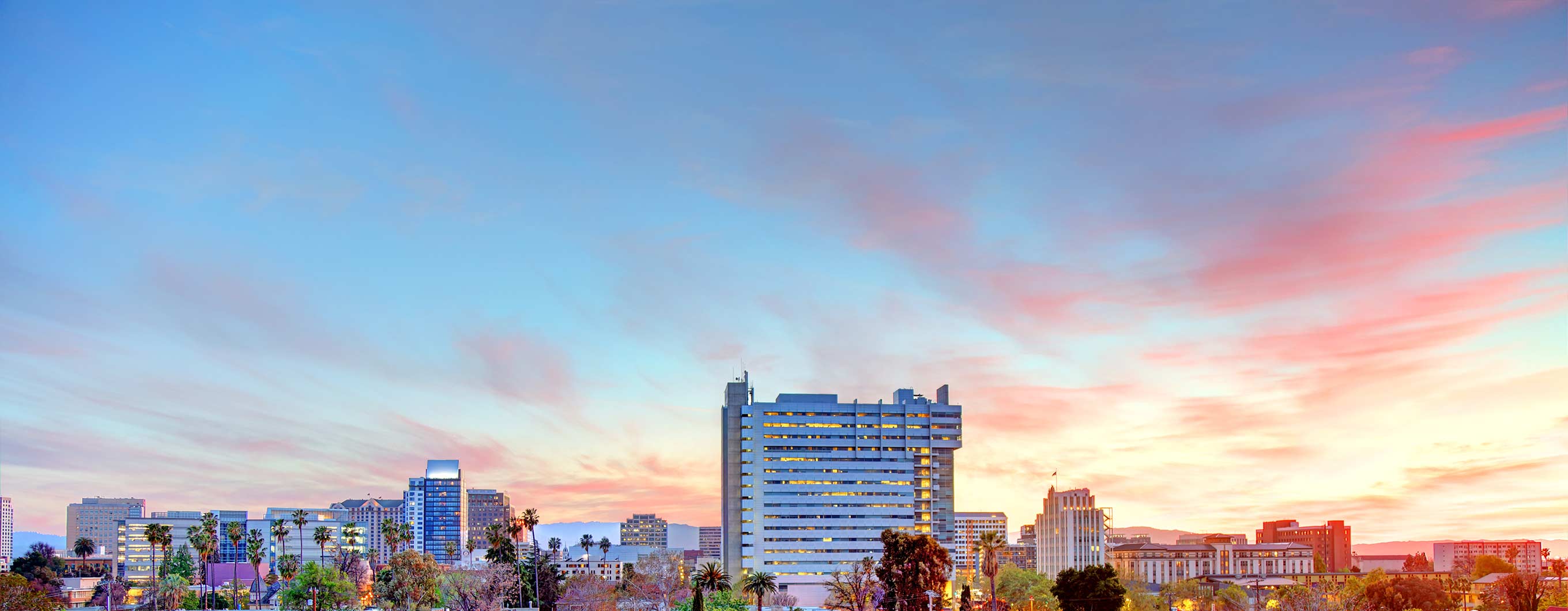 San Jose skyline at sunset, with pink clouds on the right. 