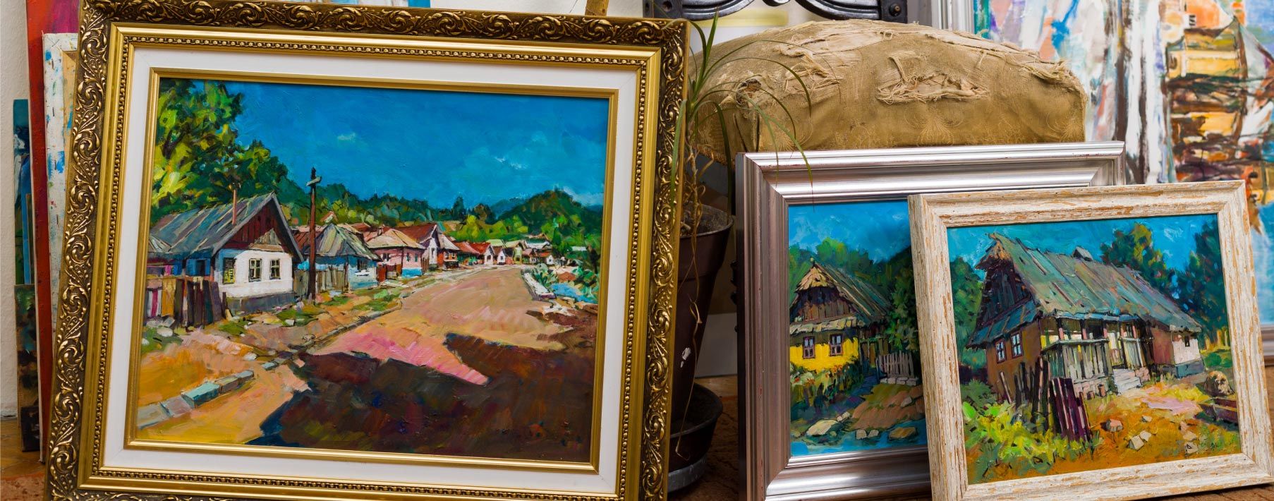 Several pieces of art leaning against plants and boxes