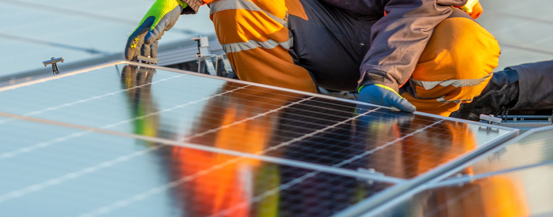 Person in construction gear working on a solar panel on a roof