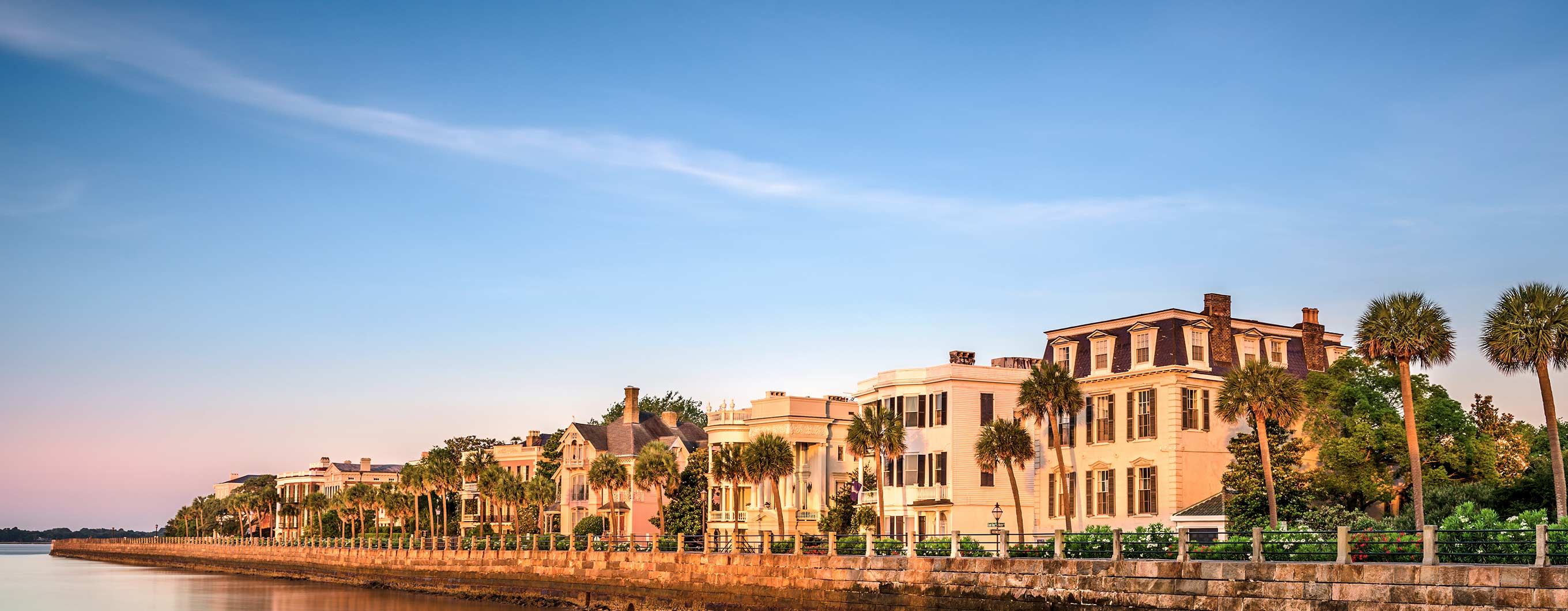 Image of buildings by the water front with palm trees and a blue sky