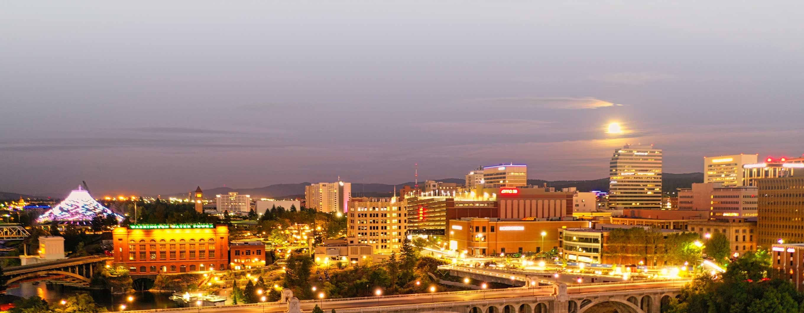 The Spokane skyline in the evening, with the buildings lit up.