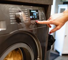 A woman's hand touching buttons on a washing machine