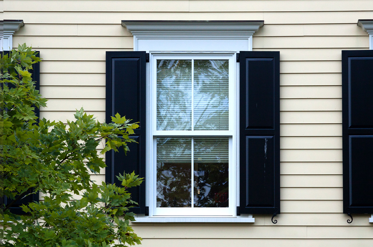 window with black window shutters on the side of a home