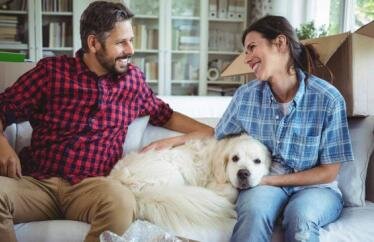 homeowners sitting on the couch with their dog while they're taking a break from unpacking