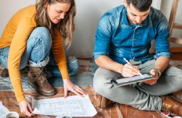 couple looking at plans on the floor of their home and preparing for home upgrades